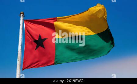 Die Fahne von Guinea-Bissau, flattert im Wind, isoliert, gegen den blauen Himmel Stockfoto