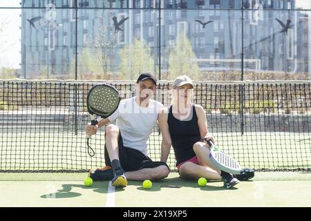 Sportpaare mit Padel-Schlägern, die auf dem Tennisplatz posieren Stockfoto