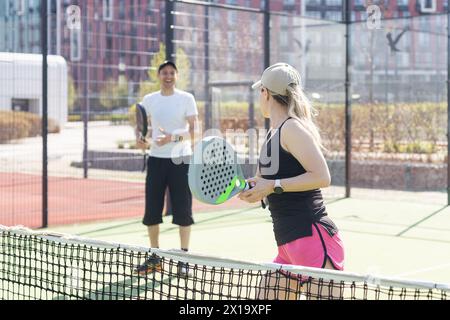Sportpaare mit Padel-Schlägern, die auf dem Tennisplatz posieren Stockfoto