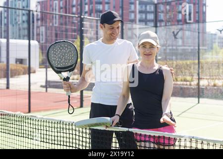 Sportpaare mit Padel-Schlägern, die auf dem Tennisplatz posieren Stockfoto