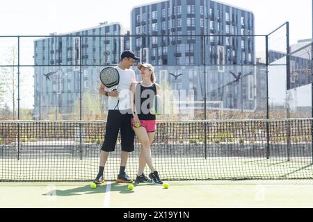Sportpaare mit Padel-Schlägern, die auf dem Tennisplatz posieren Stockfoto