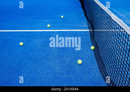 Fünf Bälle auf einem blauen Paddle-Tennisplatz in der Nähe des Netzes Stockfoto