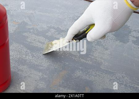 Entfernen von altem Lack von einer Holzoberfläche mit einem Teigschaber Stockfoto