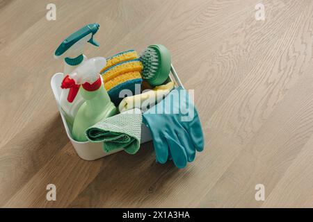 Bürsten, Flaschen mit Reinigungsflüssigkeit, Schwämme und Gummihandschuhe. Reinigungsmittel auf Holzboden. Stockfoto