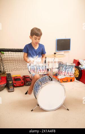 Junge, Schlagzeug und Lernen im Schlafzimmer für Talent, Musik und kreative Entwicklung in der Wohnung. Kind, Lernen und Üben im Haus für Fähigkeiten Stockfoto
