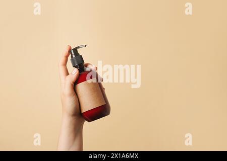 Braune kosmetische Sprühflasche in einer weiblichen Hand auf beigem Hintergrund, Platz für Text Stockfoto