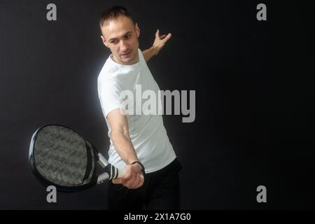 Porträt eines Mannes, der Paddeltennis spielt, in Position, um einen schwarzen, isolierten Hintergrund zu treffen. Vorderansicht. Stockfoto