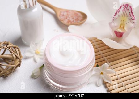 Wunderschöne Spa-Komposition mit Kosmetikprodukten und Blumen auf weißem Tisch Stockfoto