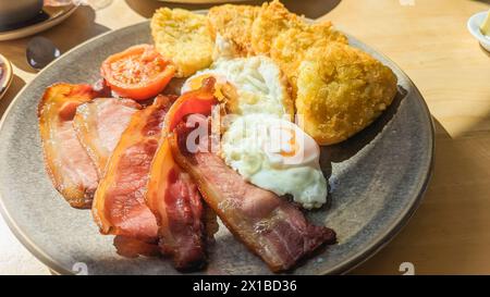 Traditionelles englisches Frühstück mit Speck, Eiern, Tomaten und Kartoffelrösti Stockfoto