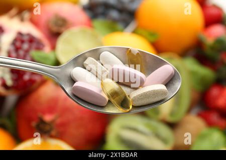 Verschiedene Vitaminpillen im Löffel über frischem Obst, Blick von oben Stockfoto