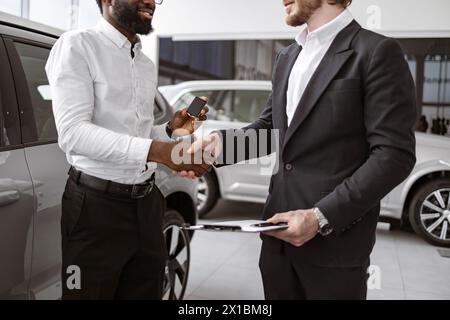 Zugeschnittene Ansicht eines afrikanischen Mannes, der Hand mit dem Fahrzeugverkäufer schüttelt. Stockfoto