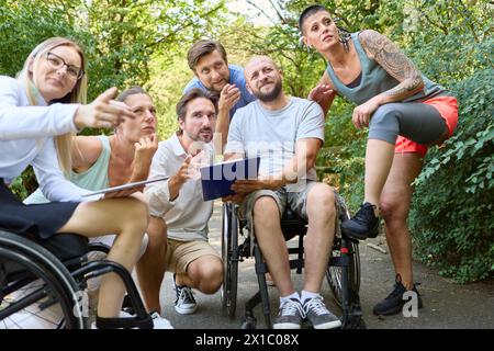 Eine Gruppe von Freunden, die sich mit einem Rollstuhl unterhalten und einen Tag in der Natur genießen. Stockfoto