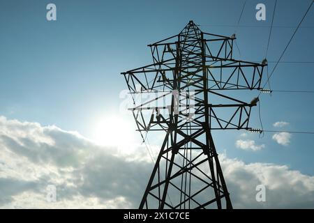 Telefonmast und Kabel gegen blauen Himmel mit Wolken Stockfoto