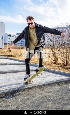 Junger Mann, der auf einem Skateboard fährt und Tricks und Sprünge macht Stockfoto