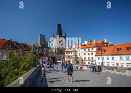 Touristen, die auf der Karlsbrücke mit gotischen Türmen in Prag spazieren. Stockfoto