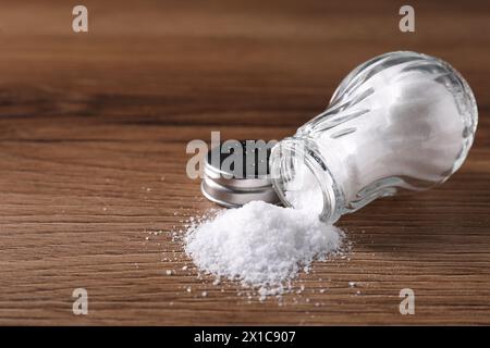 Umgedrehter Shaker mit Salz auf Holztisch. Leerzeichen für Text Stockfoto