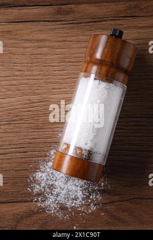 Umgedrehter Shaker mit Salz auf Holztisch, Blick von oben Stockfoto