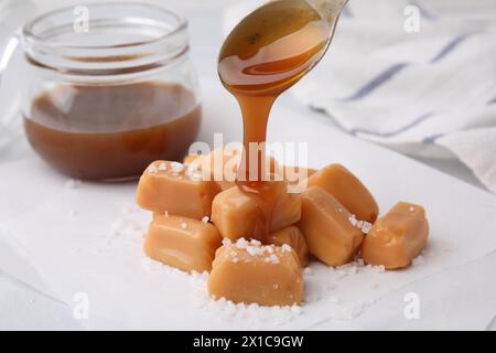 Köstliches gesalzenes Karamell auf Süßigkeiten auf weißem Tisch gießen Stockfoto