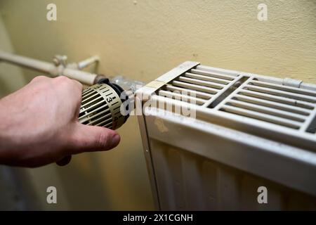 Augsburg, Bayern, Deutschland - 13. April 2024: Ein Mann dreht den Thermostat an einem Heizkörper. Heizung *** die Hand von einem Mann dreht am Thermostat von einem Heizkörper. Heizung Stockfoto