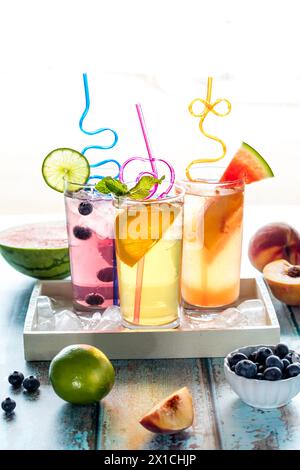 Erfrischendes Wasser mit Fruchtgeschmack in einem Tablett mit Eis, umgeben von Obst Stockfoto