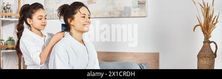 Eine brünette Mutter und Tochter in weißen Bademänteln stehen zusammen und zeigen eine starke Verbundenheit. Stockfoto