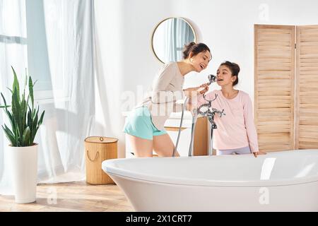 Eine brünette Frau und ihre Tochter stehen in einem modernen Badezimmer nebeneinander während ihrer Schönheits- und Hygienearbeit. Stockfoto