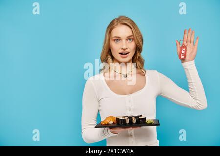 Eine blonde Frau hält anmutig ein Tablett asiatischer Küche mit Verkaufsschild in der Hand. Stockfoto