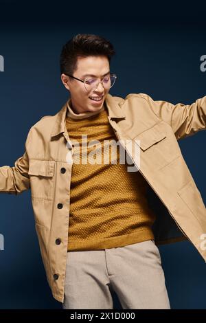 Ein modischer junger Mann in Brille und brauner Jacke posiert und strahlt Selbstvertrauen und Raffinesse aus. Stockfoto