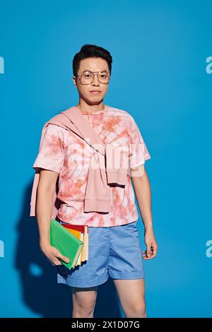 Ein stilvoller junger Mann posiert vor einer leuchtend blauen Wand und strahlt Selbstvertrauen und Charisma aus. Stockfoto