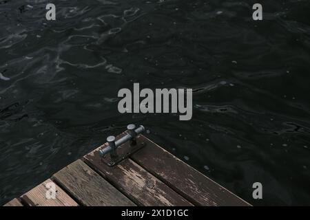 Ein Metallpfosten und sein Schatten auf einem alten hölzernen Hafensteg. Hintergrund. Blick von oben. Stockfoto