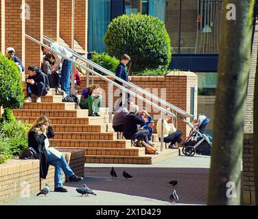 Glasgow, Schottland, Großbritannien. 16. April 2024: Wetter in Großbritannien: Studenten des Royal conservatoire of scotland sonnen sich auf den Eingangspunkten des College. Sonnig in der Stadt, während die Leute auf der Buchanan Street, der Einkaufshauptstadt und der stilvollen Meile Schottlands, spazierten. Credit Gerard Ferry/Alamy Live News Stockfoto