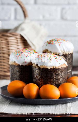 Nahaufnahme von glasierten Osterkuchen und orangefarbenen Eiern auf einem Teller. Stockfoto