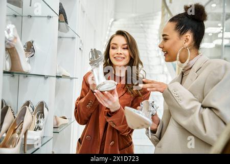 Zwei junge Frauen, darunter eine wunderschöne Braut, erkunden stilvolle Schuhe in einem Geschäft, während sie für eine Hochzeit einkaufen. Stockfoto