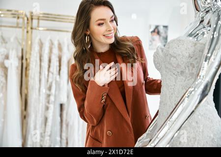 Eine junge, schöne Braut steht in Ehrfurcht, als sie ein Hochzeitskleid auf einer Schaufensterpuppe ansieht und das perfekte Kleid sucht Stockfoto