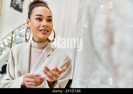 Eine junge Braut kauft ihr Hochzeitskleid ein, steht vor einem Spiegel und Kleidern Stockfoto