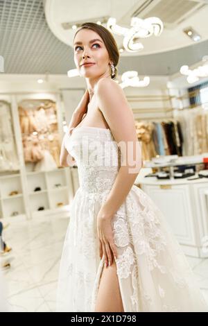 Eine junge brünette Braut posiert in einem weißen Kleid und strahlt Eleganz und Schönheit bei einem Fotoshooting in einem Hochzeitssalon aus. Stockfoto