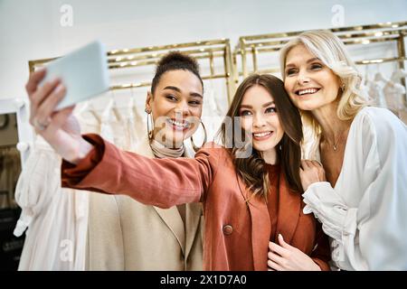 Zwei junge Frauen, eine zukünftige Braut und ihre beste Freundin, posieren beim Selfie in einem trendigen Bekleidungsgeschäft. Stockfoto