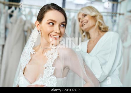 Eine junge brünette Braut im Hochzeitskleid steht neben ihrer Mutter mittleren Alters Stockfoto