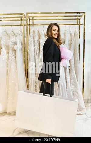 Eine junge brünette Braut steht vor einem Kleiderständer in einem Hochzeitssalon und versucht, sich für ihr perfektes Kleid zu entscheiden. Stockfoto