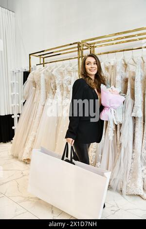 Eine junge brünette Braut steht vor einem Kleiderständer in einem Hochzeitssalon und wählt sorgfältig ihr perfektes Kleid aus. Stockfoto
