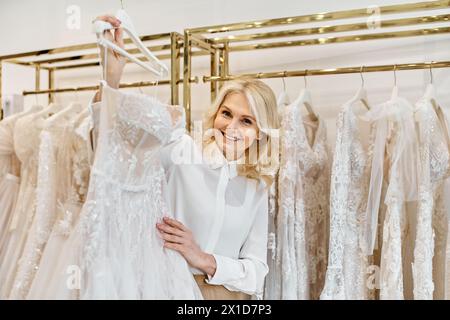 Ein wunderschöner Einkaufsassistent mittleren Alters steht anmutig vor einem Regal eleganter Brautkleider in einem Brautsalon. Stockfoto