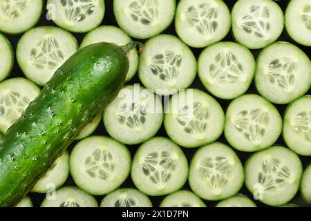 Reife Gurken und geschnittene Gurkenscheiben auf dunklem Hintergrund, Draufsicht Stockfoto