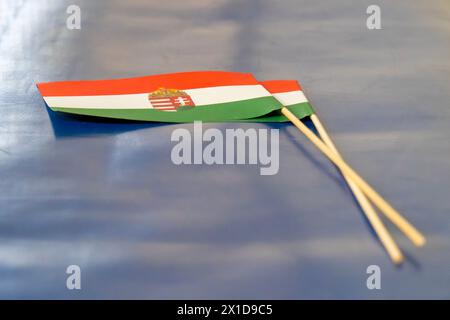 Kleine ungarische Nationalflaggen aus Papier mit Wappen auf blauem Hintergrund Stockfoto