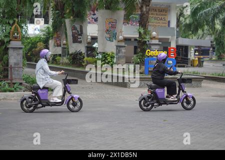 Mehrere Mädchen fahren Elektrofahrräder mit Helmen auf dem Campus Stockfoto