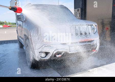 Autowäsche mit Seife aus einem Schlauch im Freien. Auto in Schaum Stockfoto
