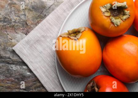 Köstliche reife Persimmons auf dem strukturierten Tisch, Blick von oben. Leerzeichen für Text Stockfoto