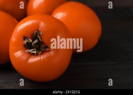 Köstliche reife Persimmons auf dunklem Holztisch, Nahaufnahme Stockfoto