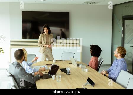 Die kompetente Frau präsentiert sich während eines Meetings vor Kollegen, wobei ihr Ausdruck Begeisterung und Führungsstärke zum Ausdruck bringt Stockfoto