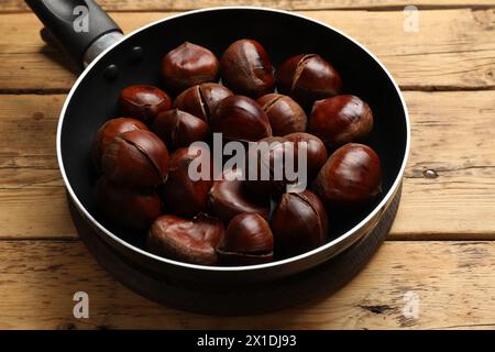 Frische essbare süße Kastanien in der Pfanne auf Holztisch Stockfoto