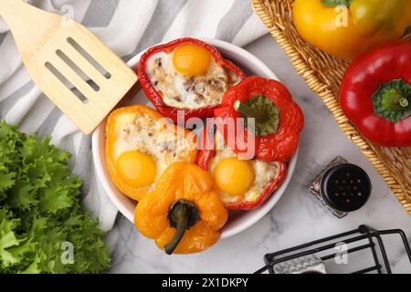 Köstliche gefüllte Paprika in einer Schüssel mit Zutaten und Spachtel auf weißem Marmortisch, flach gelegt Stockfoto